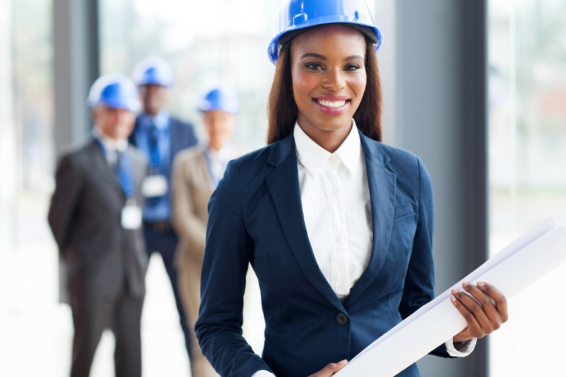 A woman in a hardhat holding architectural designs. 